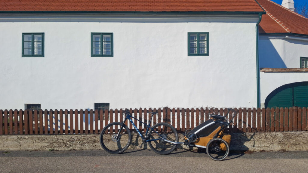 Bicykel Trek opretí aj s cyklovozíkom Thule Chariot Sport 2 o plot pri cyklovýlete v Rakúskom údolí Wachau