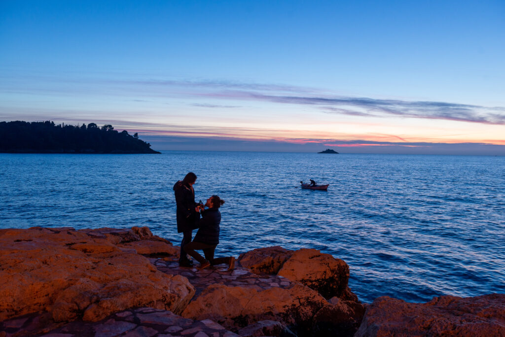Michal Mjartan požiadal Marcelu Mjartan o ruku na Istrii v meste Rovinj na pobreží. Na mori loďka. On kľačí a drží zásnubný prsteň.
