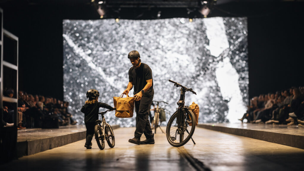 Večerná show THEX a ukažka otca a syna pričom otec drží Thule brašňu na bicykel s novinkou InLock