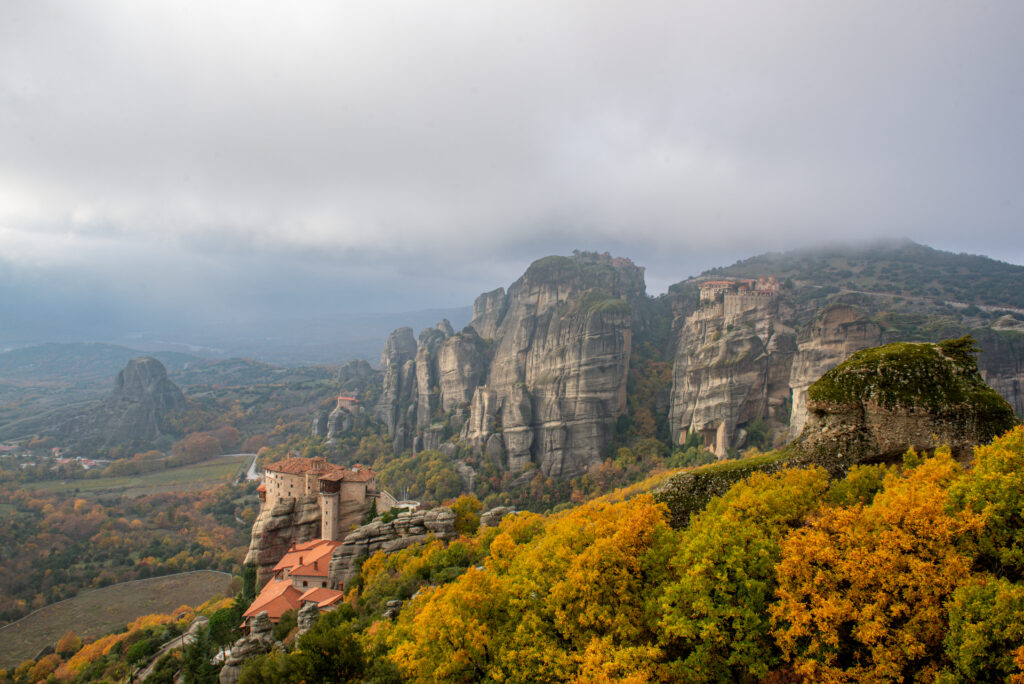 Pohľad na kláštor v Gréckej Meteora. Jesenné farebné stromy a jemne zatiahnutá obloha.