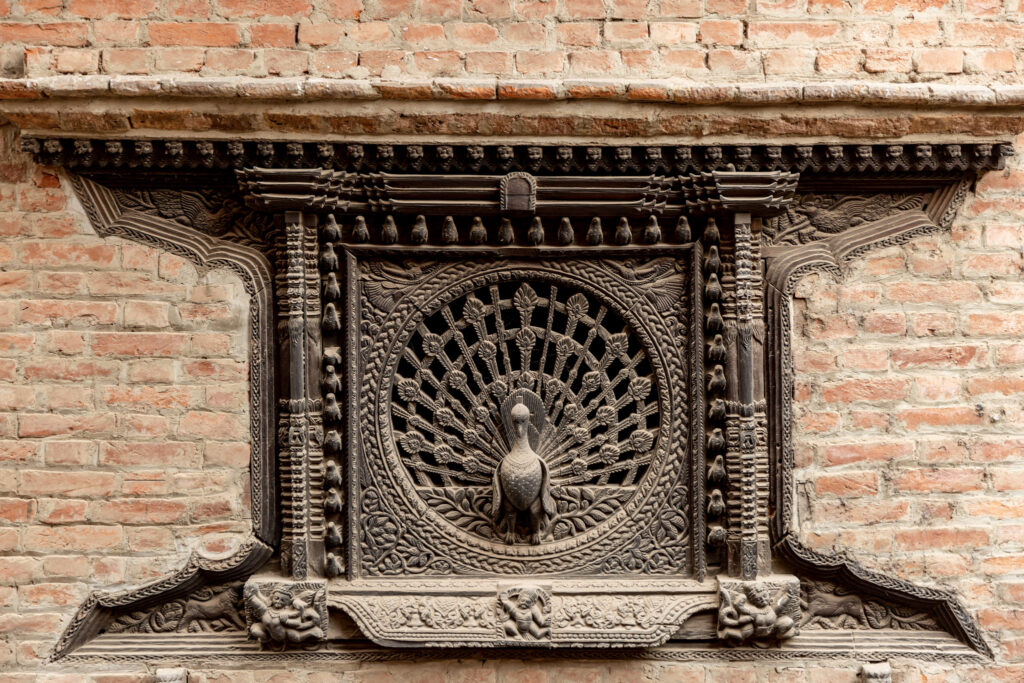 Drevené, detailne vyrezávané okno  v tvare páva v Bhaktapur