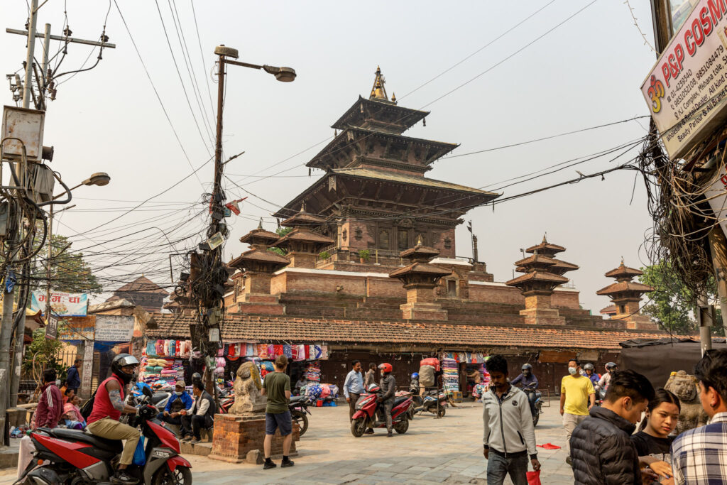 Rušná časť Durbar Square v Káthmandu plná ľudí, obchodov a motoriek