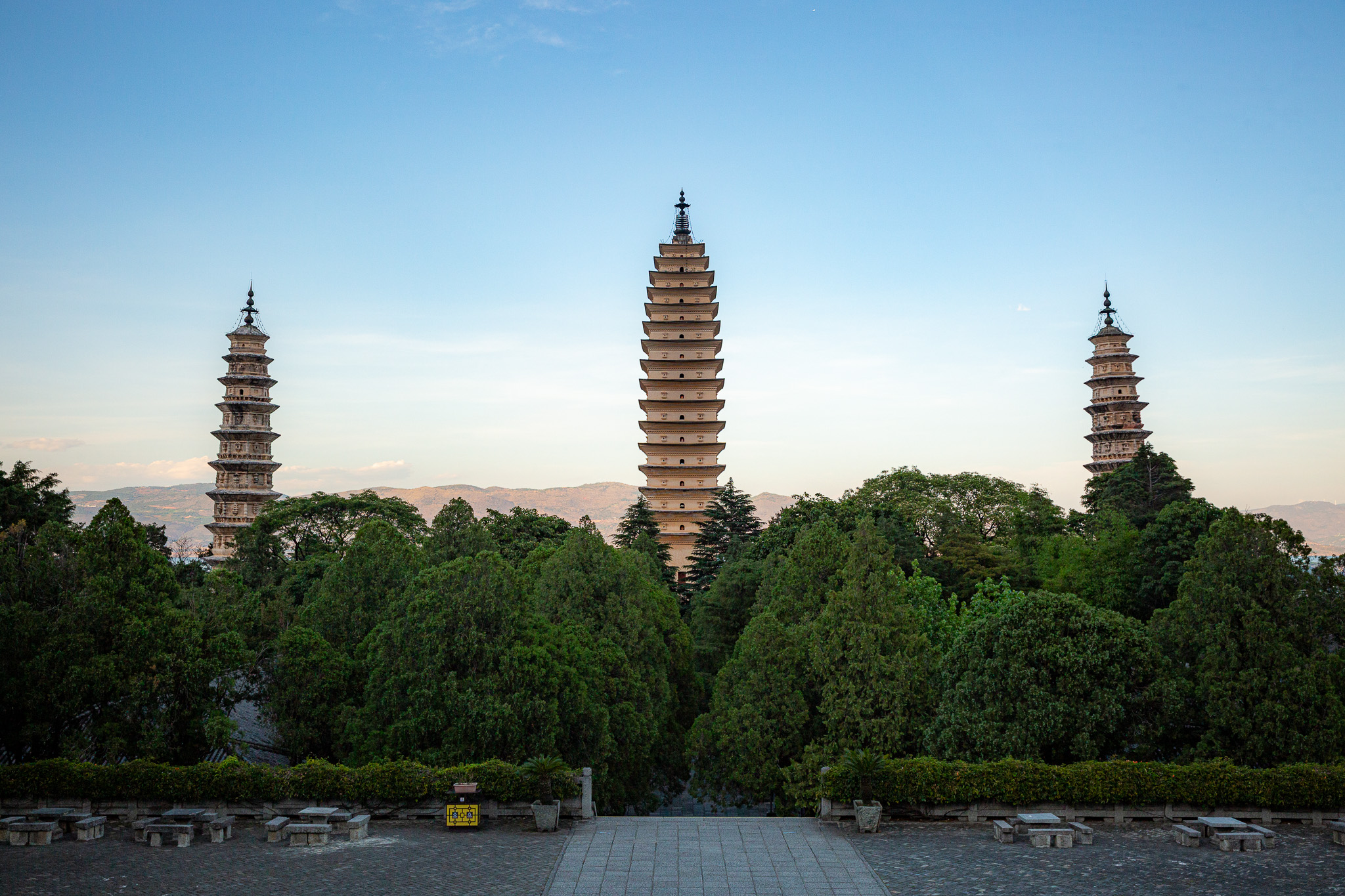 Three Pagodas pred ktorými sú stromi, spoza ktorých trčia. Dali, Yunnan, Čína
