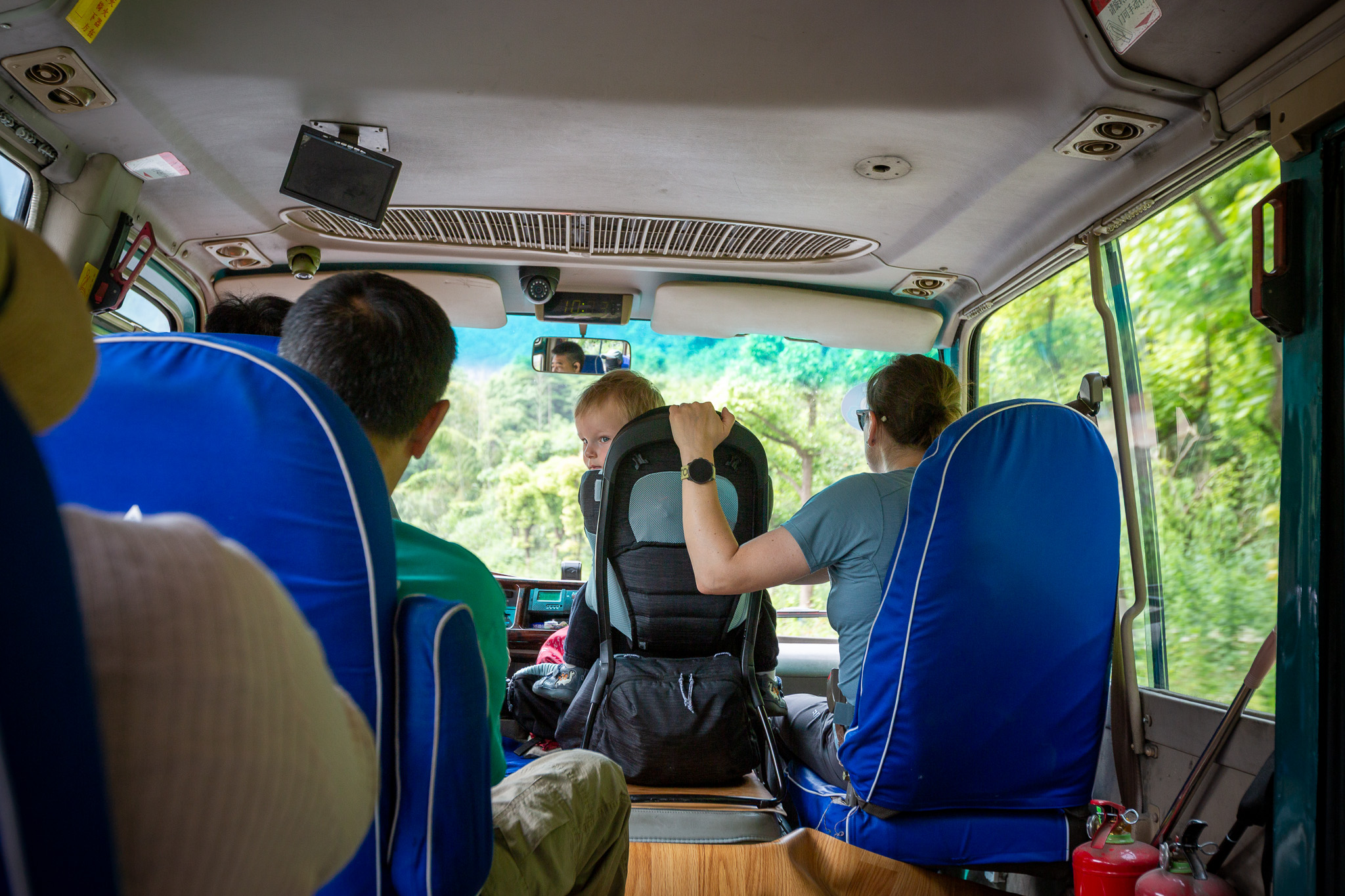 Maca so synom Markusom (matka s malým dieťaťom v turistickom nosiči) sedia v autobuse počas cesty od vchodu k lanovke na Tianmen Mountain v meste Zhangjiajie, Čína.