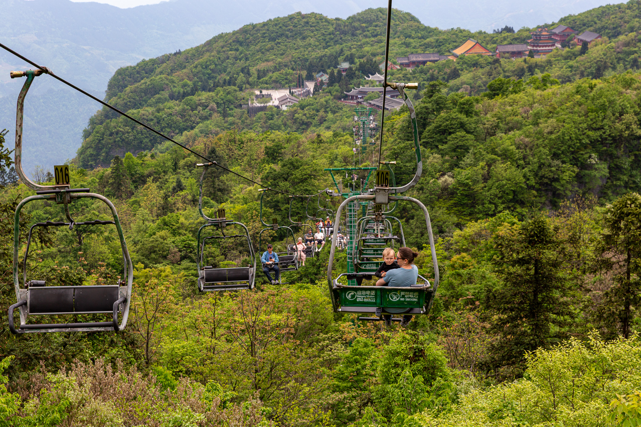 Pohľad zo sedačkovej lanovky na vrchu hory Tianmen v Číne, smerujúcej nad hustým zeleným lesom k budhistickému chrámu Tianmen Mountain Temple.