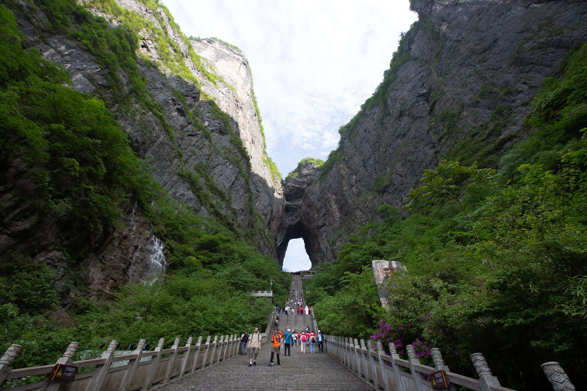 Turisti na dlhom schodisku vedúcemu k slávnemu skalnému oknu Nebeská brána na Tianmen Mountain v oblasti Zhangjiajie, Čína.