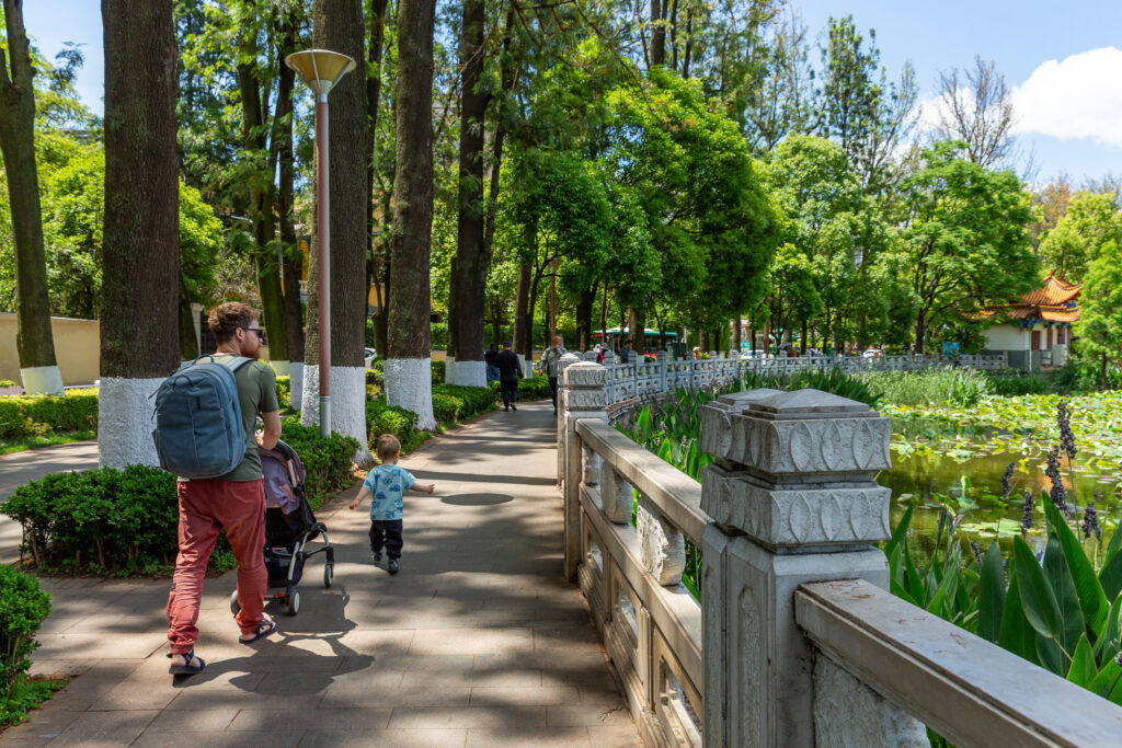Mišo so synom Markusom v (otec s malým dieťaťom) kráčajú okolo jazierka v Green Lake parku v meste Kunming, Čína.