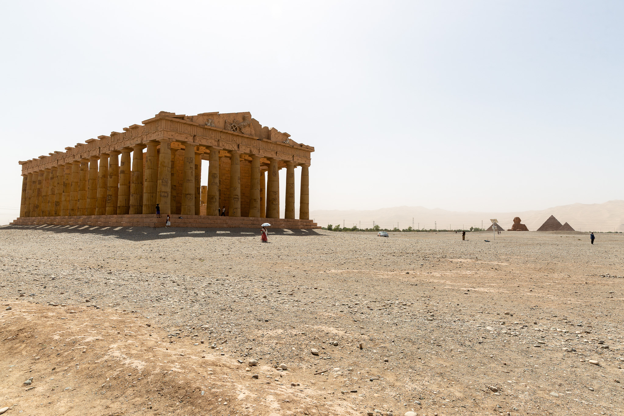 Replika gréckeho chrámu v areáli Silk Road Heritage City v Dunhuangu s miniatúrami pyramíd v púštnom pozadí.