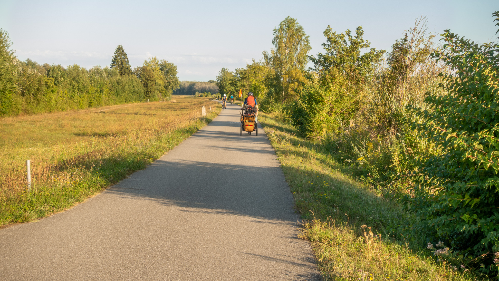 Cyklistická hrádza pri Dunaji a pohľad na cyklistu ktorý ťahá cyklovozík