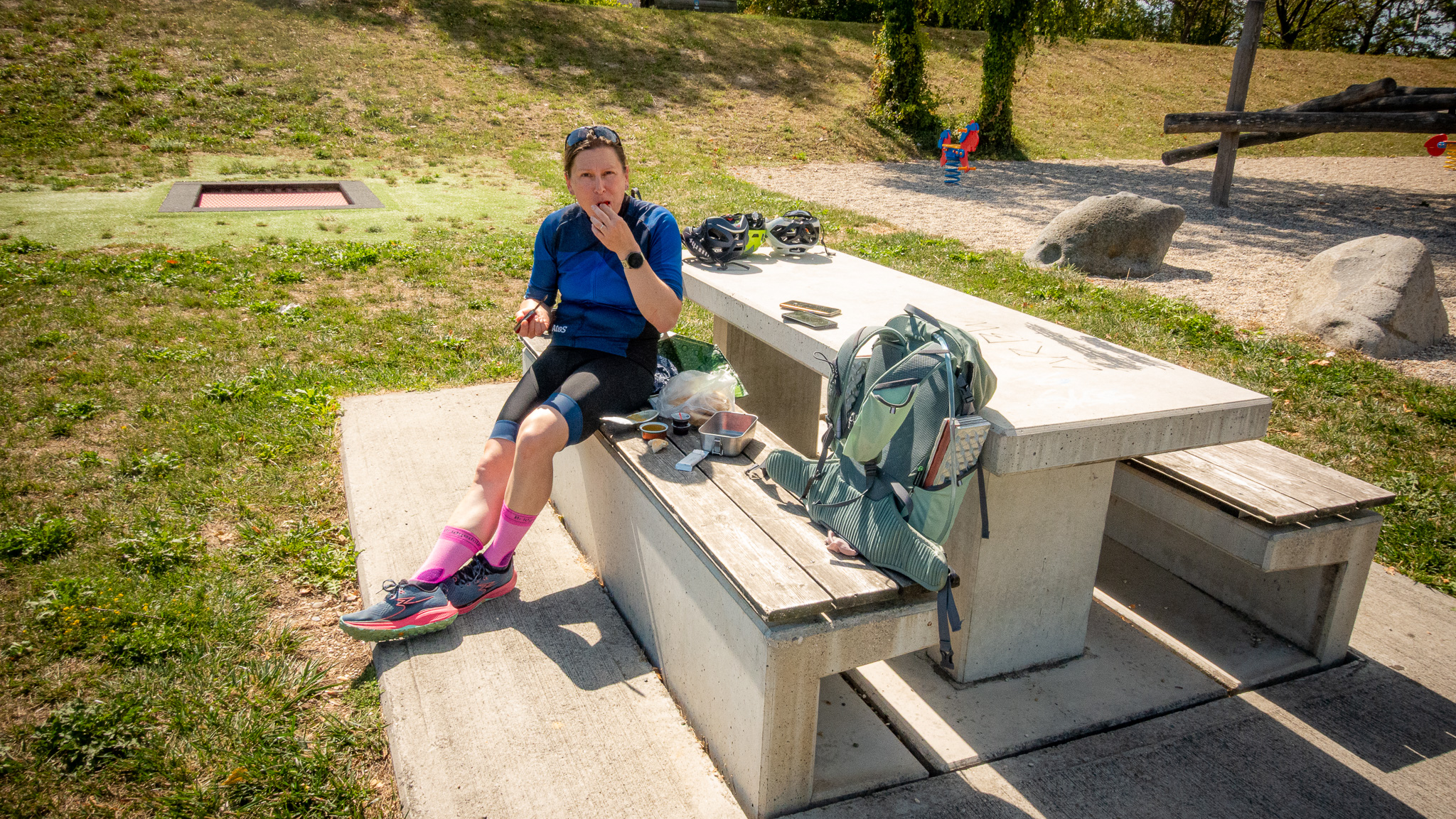 Cyklistka sedí na lavičke a obeduje
